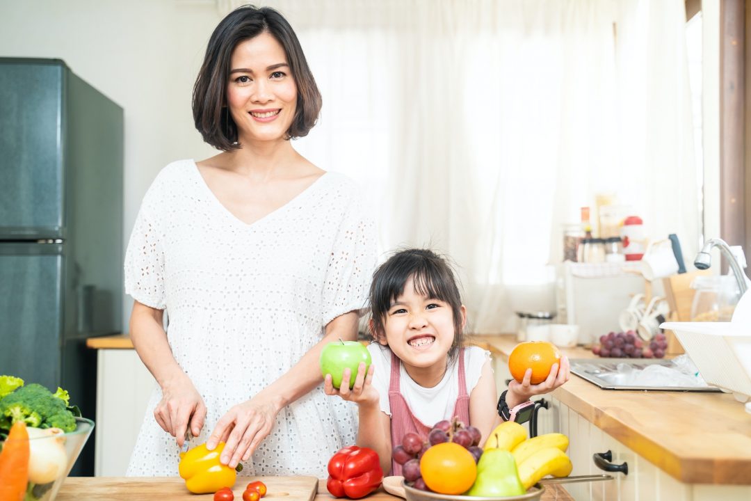 portrait of young mother preparing high nutrition foods for her kid daughter in kitchen