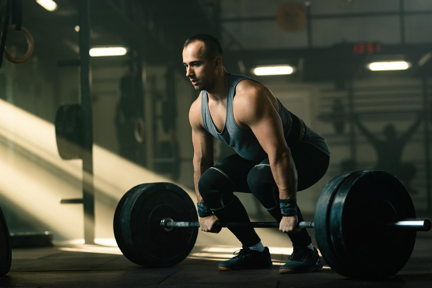 young sportsman having strength training lifting barbell gym